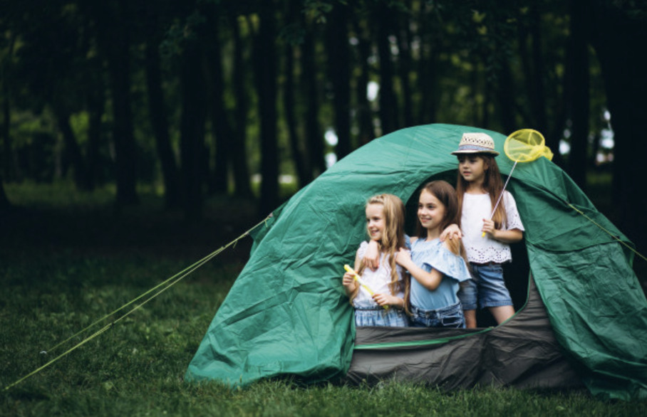 Three children in a tent in the woods