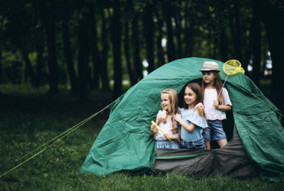 Three children in a tent in the woods