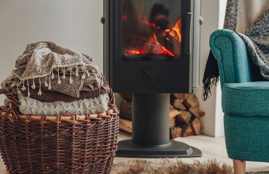 A blanket basket and an armchair in front of a log fire