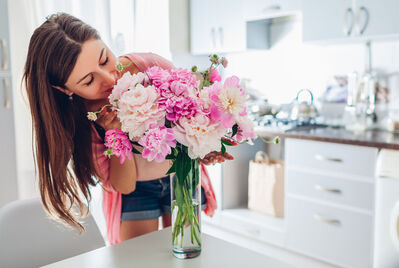 A woman arranging pink flowers on a table