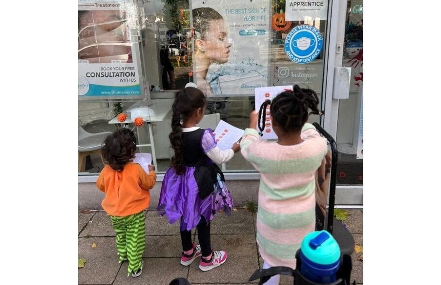 Three children gathered in front of a window with pieces of paper