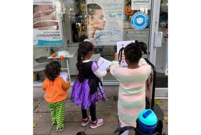 Three children gathered in front of a window with pieces of paper