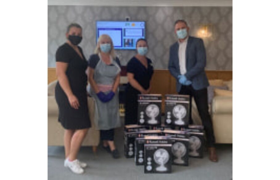 A group of people posing around boxed up fans