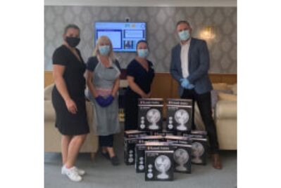 A group of people posing around boxed up fans