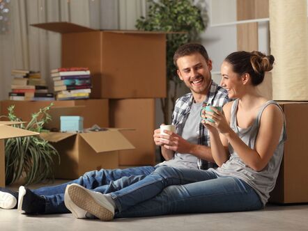 A couple laughing on the floor surrounded by boxes