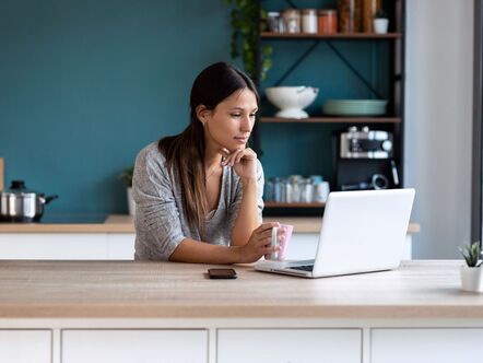 A person sitting in front of a laptop in a kitchen