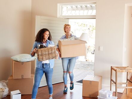 A young couple carrying boxes into a home